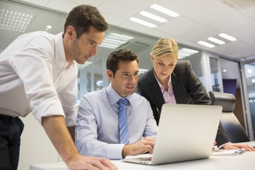A work team surrounding a laptop.